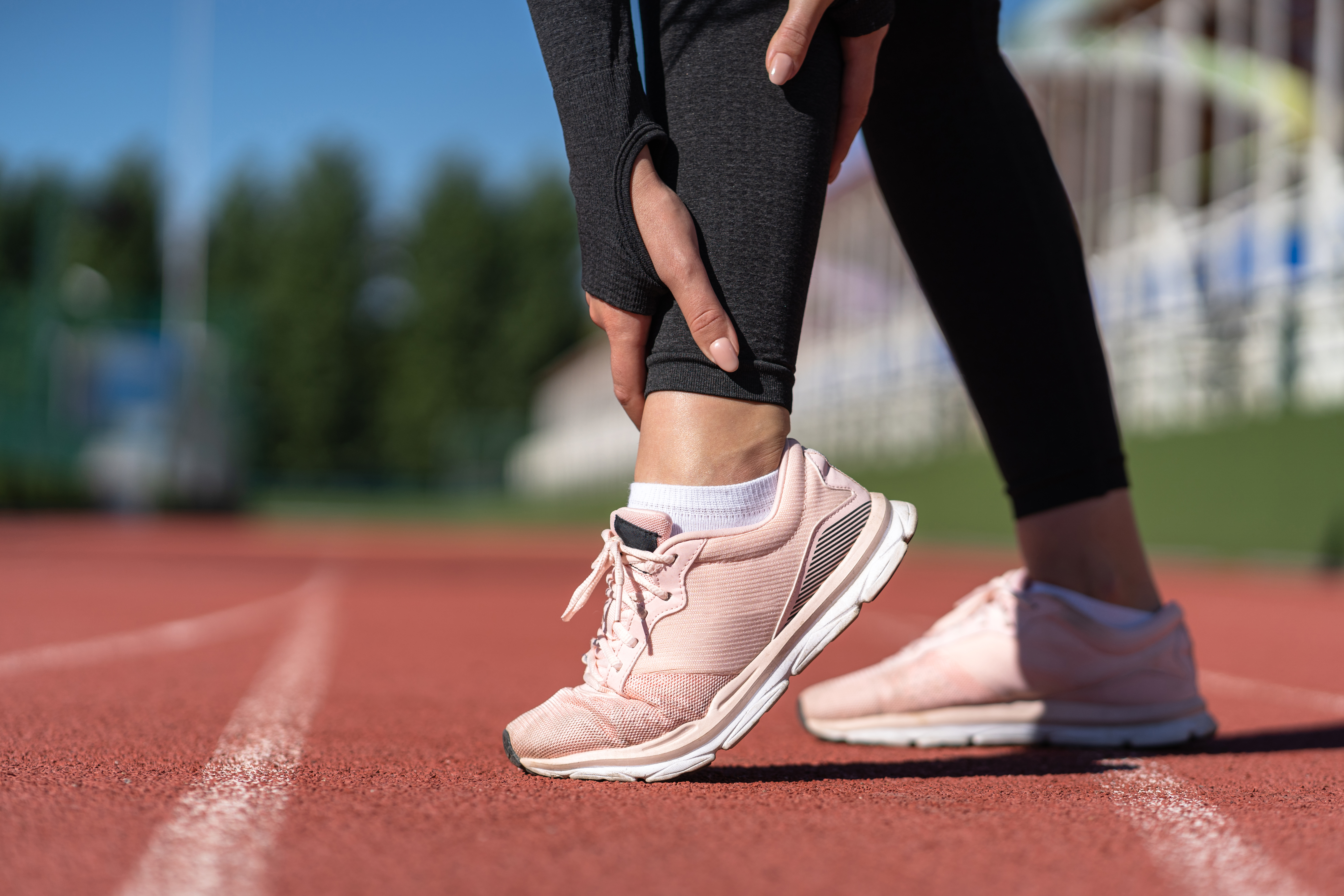 woman runner touching foot in pain due to sprained ankle. Runnin
